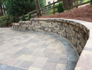 Curved segmental retaining wall with integrated bench seating and matching soldier course border on custom multi-tone paver patio