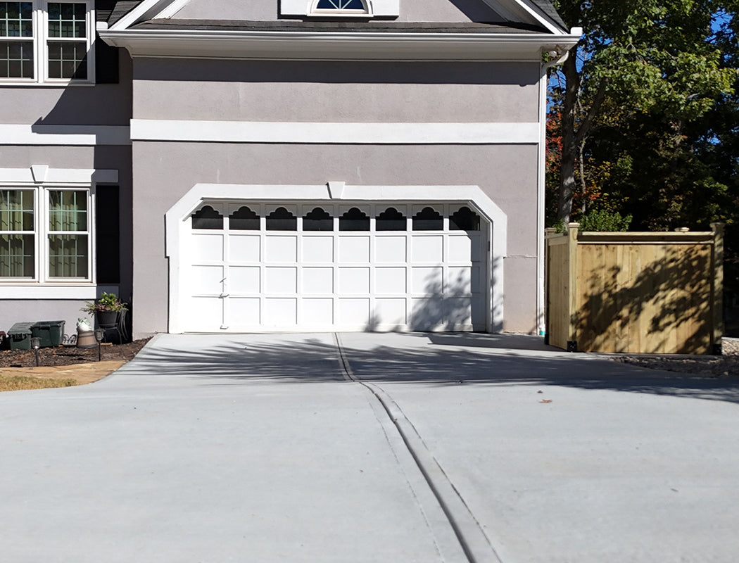 reshly installed gray concrete driveway featuring precise finishing lines, smooth surface, and tight alignment to the garage threshold. Expert concrete driveway work enhancing curb appeal in Marietta, Georgia