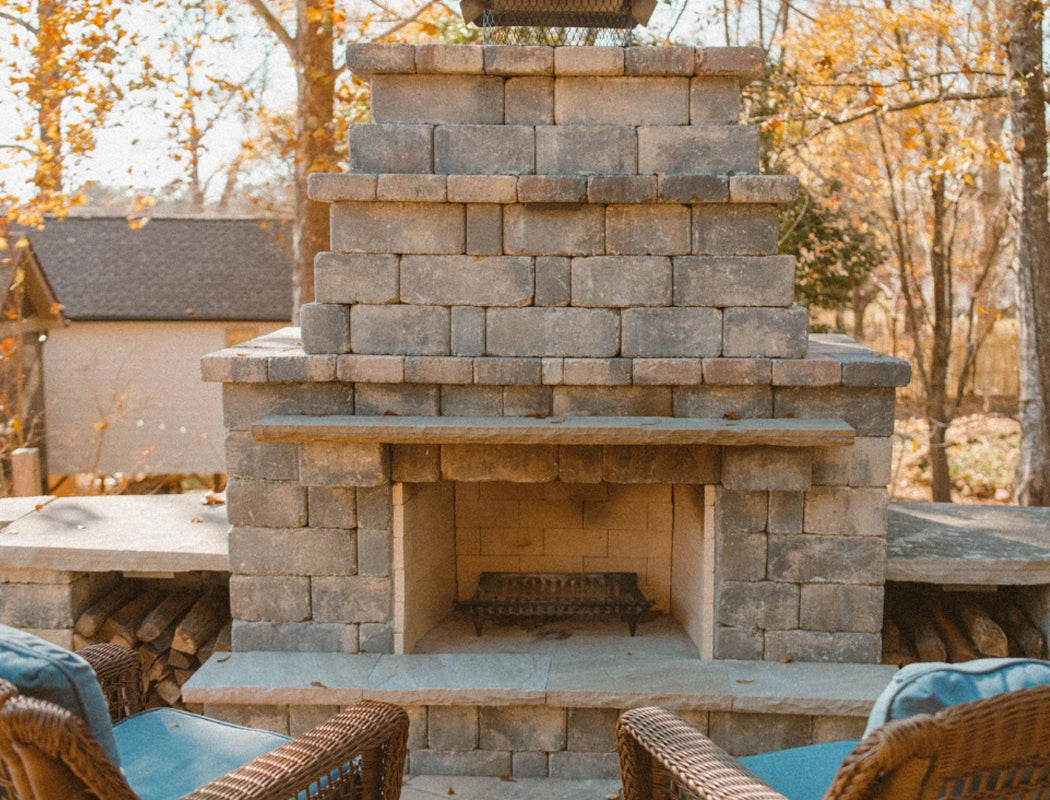 Stone outdoor fireplace with seating area in a wooded area