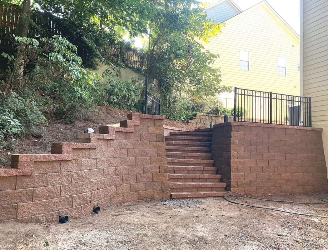 Completed project view showing a sturdy terraced retaining wall in rich red tones, featuring broad integrated staircase and clean curved design that enhances slope stability and aesthetics in Marietta, Georgia