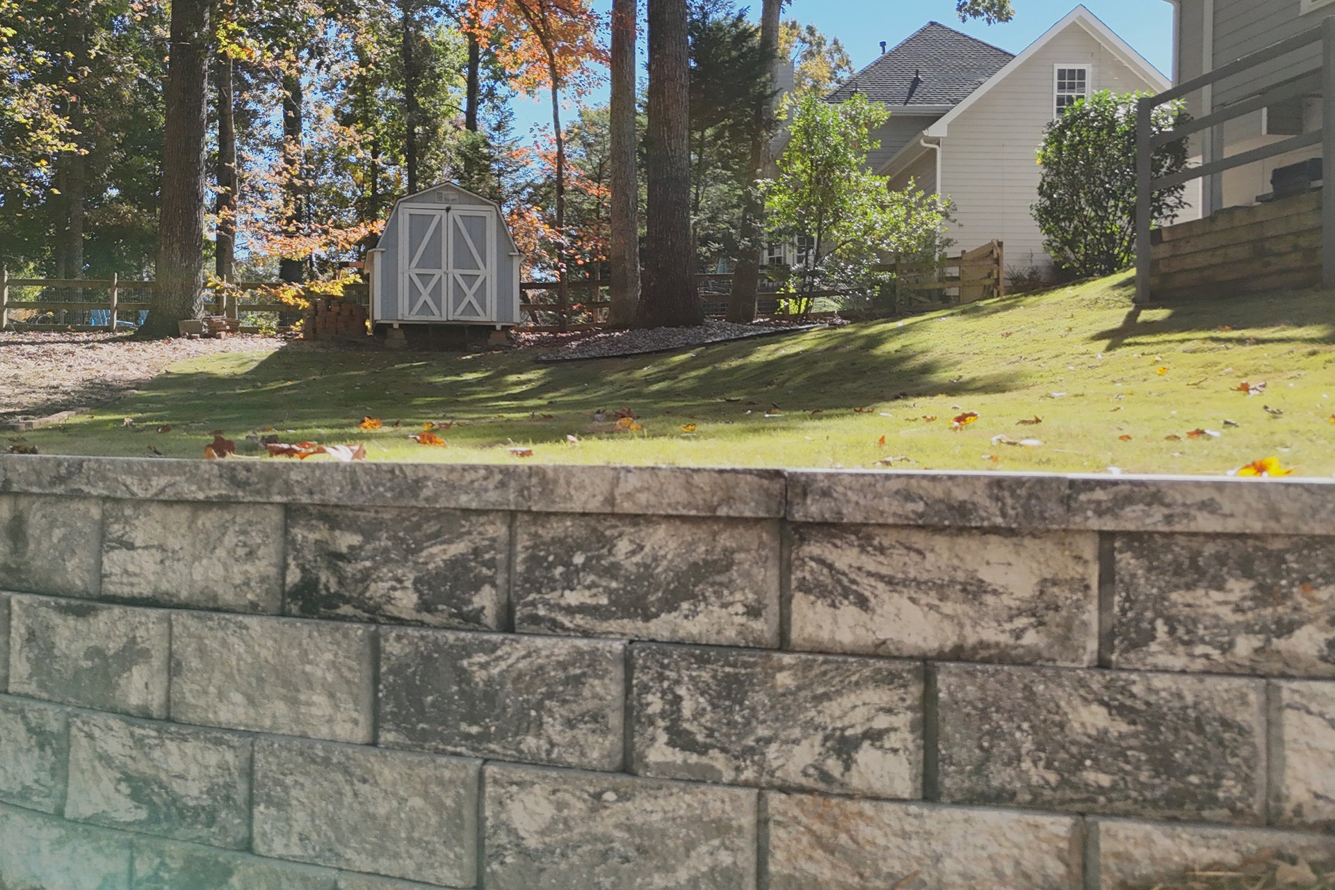 Stone wall with a grassy area and trees in the background