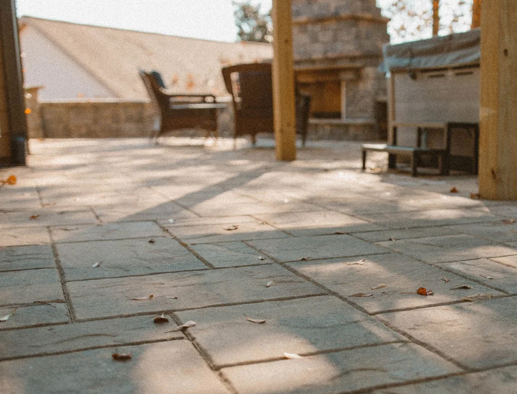 Custom paver patio featuring stone fireplace and cozy outdoor seating area under covered pergola, professional hardscaping creating inviting backyard living space in Marietta, GA – Precision Grading & Hardscapes