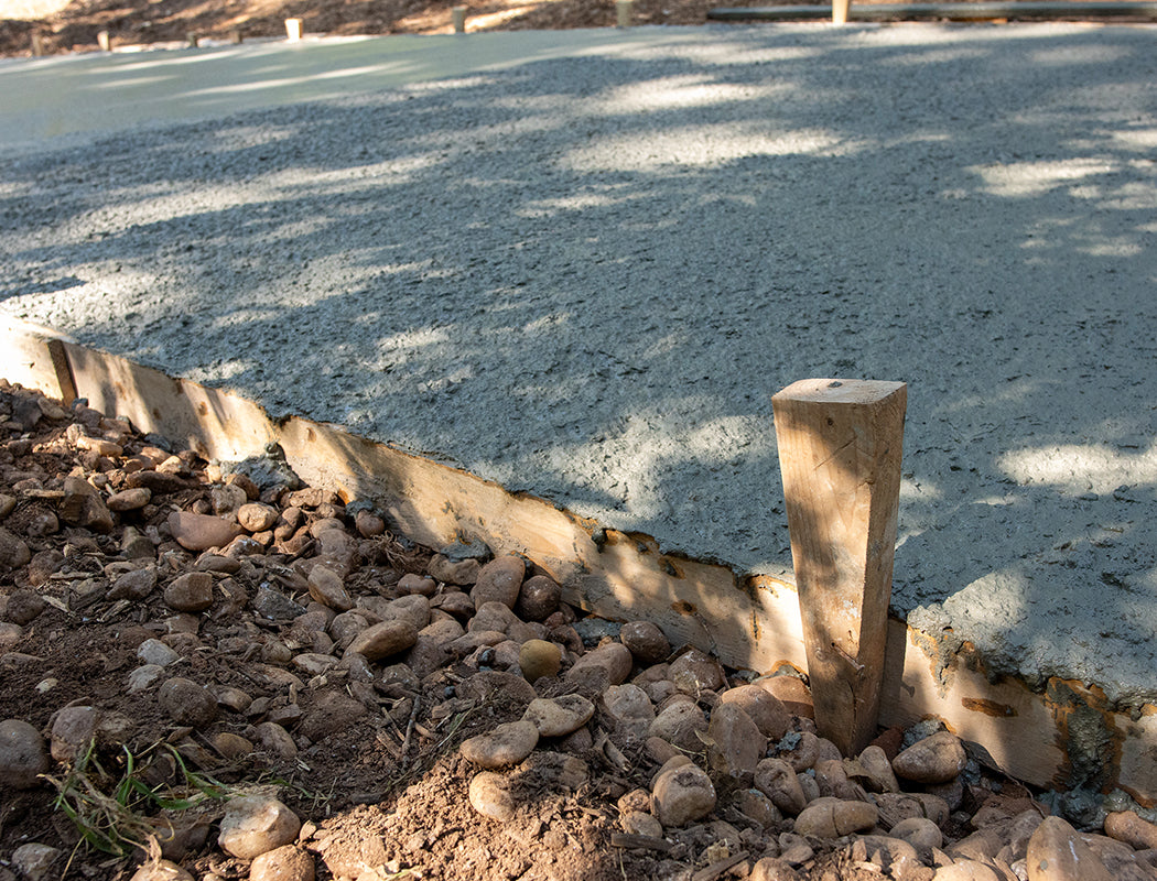 Precision Grading & Hardscapes concrete driveway construction detail: level pour with even surface texture, sturdy wooden stakes holding forms, and clean gravel bedding layer in Marietta GA