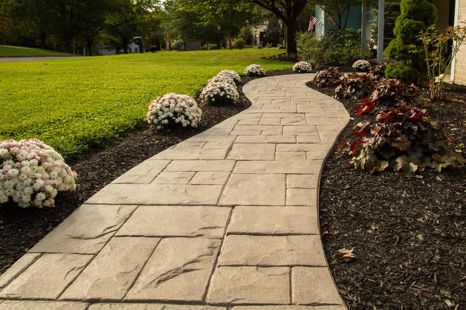 Elegant curved paver walkway with natural stone texture and vibrant flower borders