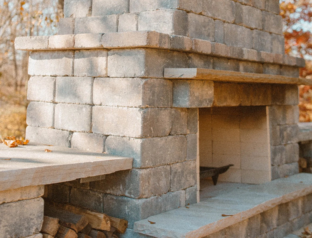 Detailed view of hand-built outdoor fireplace with textured gray stone blocks, substantial timber mantel, and spacious fire chamber ready for cozy evenings