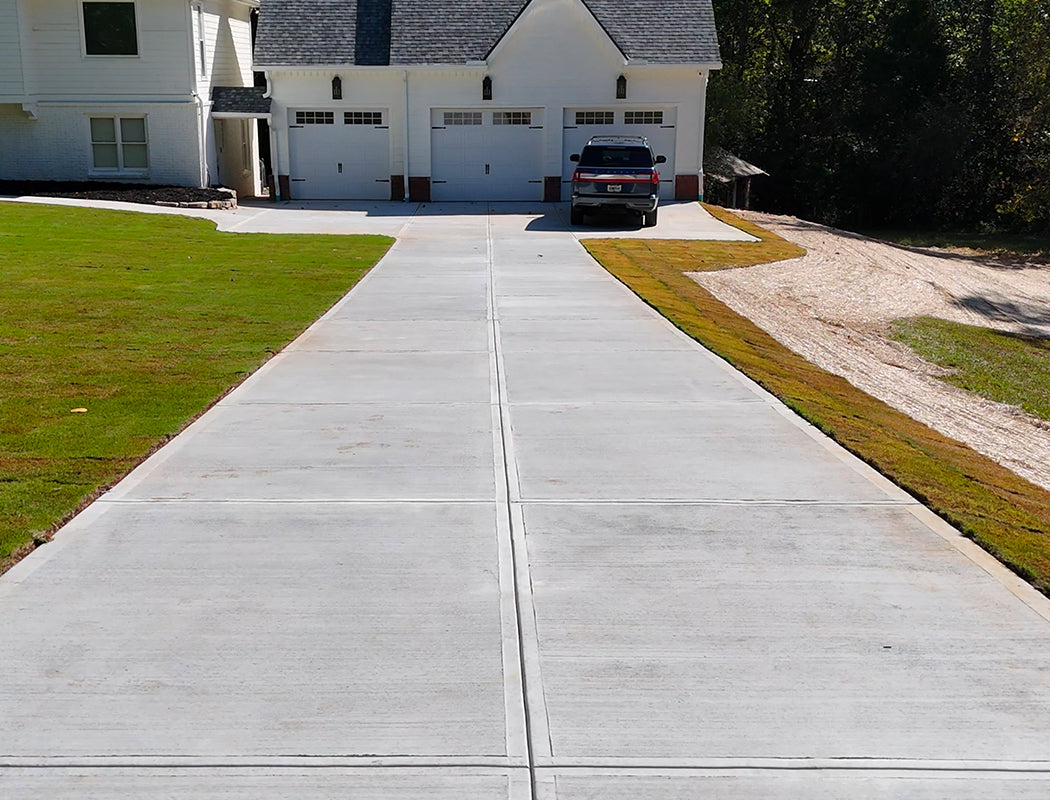 Concrete driveway leading to a house with a parked car.