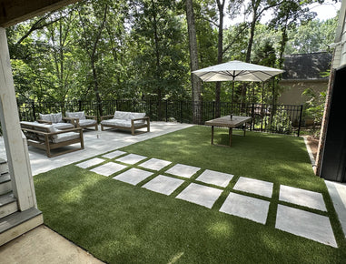Outdoor patio with green grass, white tiles, and outdoor furniture.