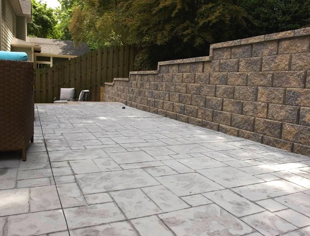 Paved patio area with a retaining wall in a backyard setting