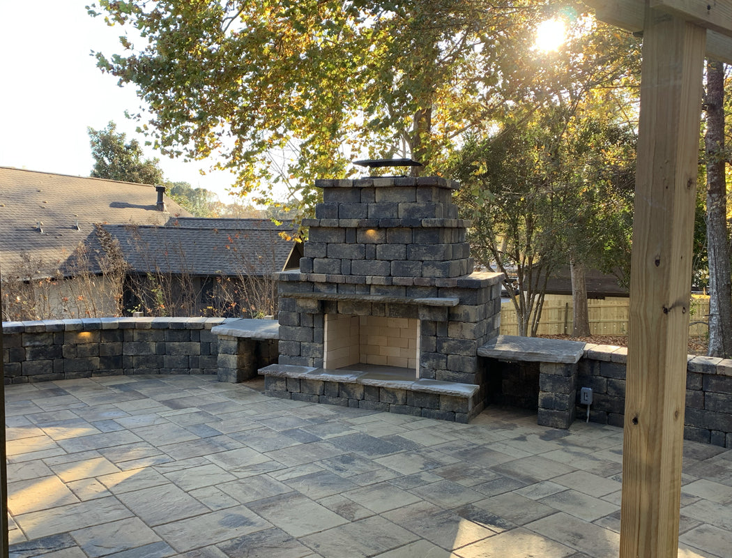 Outdoor stone fireplace and seating area with trees in the background