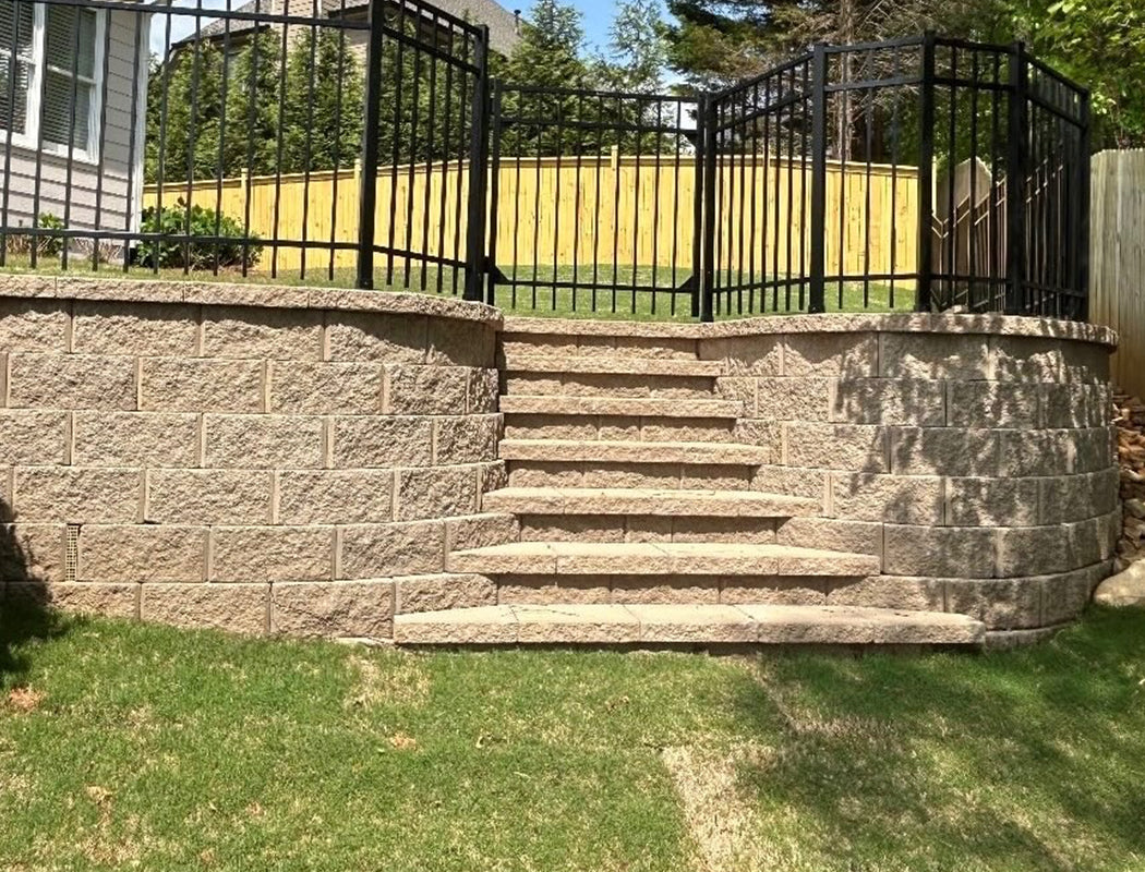 Stone steps leading up to a house with black metal fence and garden area.