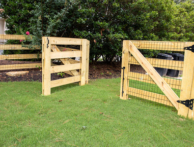 Wooden gate with wire mesh on a grassy area with trees in the background