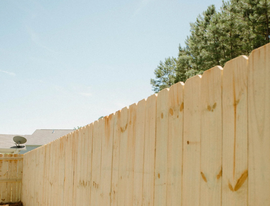Freshly built tall wooden privacy fence featuring pointed scalloped pickets and sturdy horizontal rails, creating a clean boundary for residential backyards in Marietta, Georgia