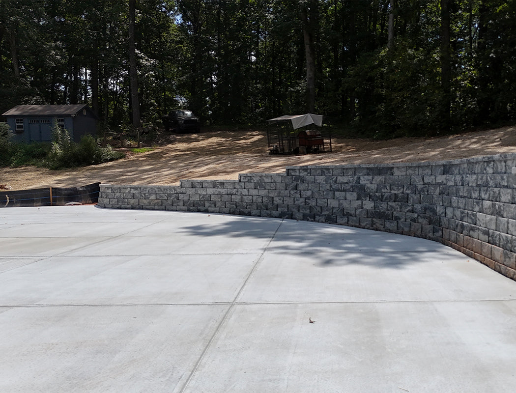 Concrete driveway with a stone retaining wall and trees in the background