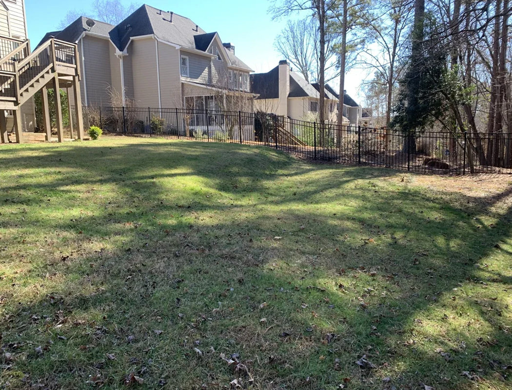 Uneven backyard with grass and a house in the background