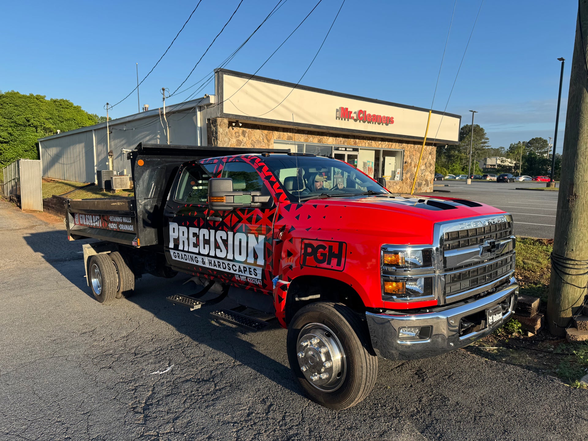 Red truck with 'Precision' and 'PGH' branding parked in front of a building.