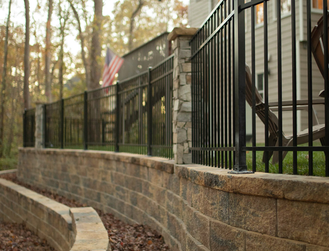 Black metal fence with stone wall and American flag in the background
