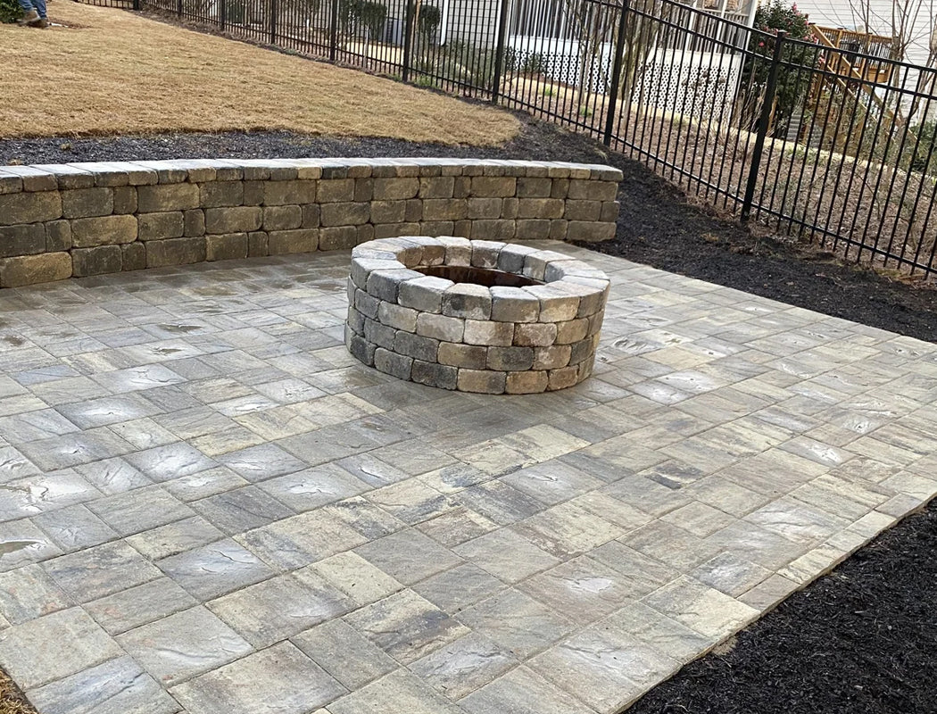 Precision Grading & Hardscapes built this inviting stamped patio with integrated fire pit focal point, low retaining wall bench, and professional grading for a sloped backyard in Marietta GA