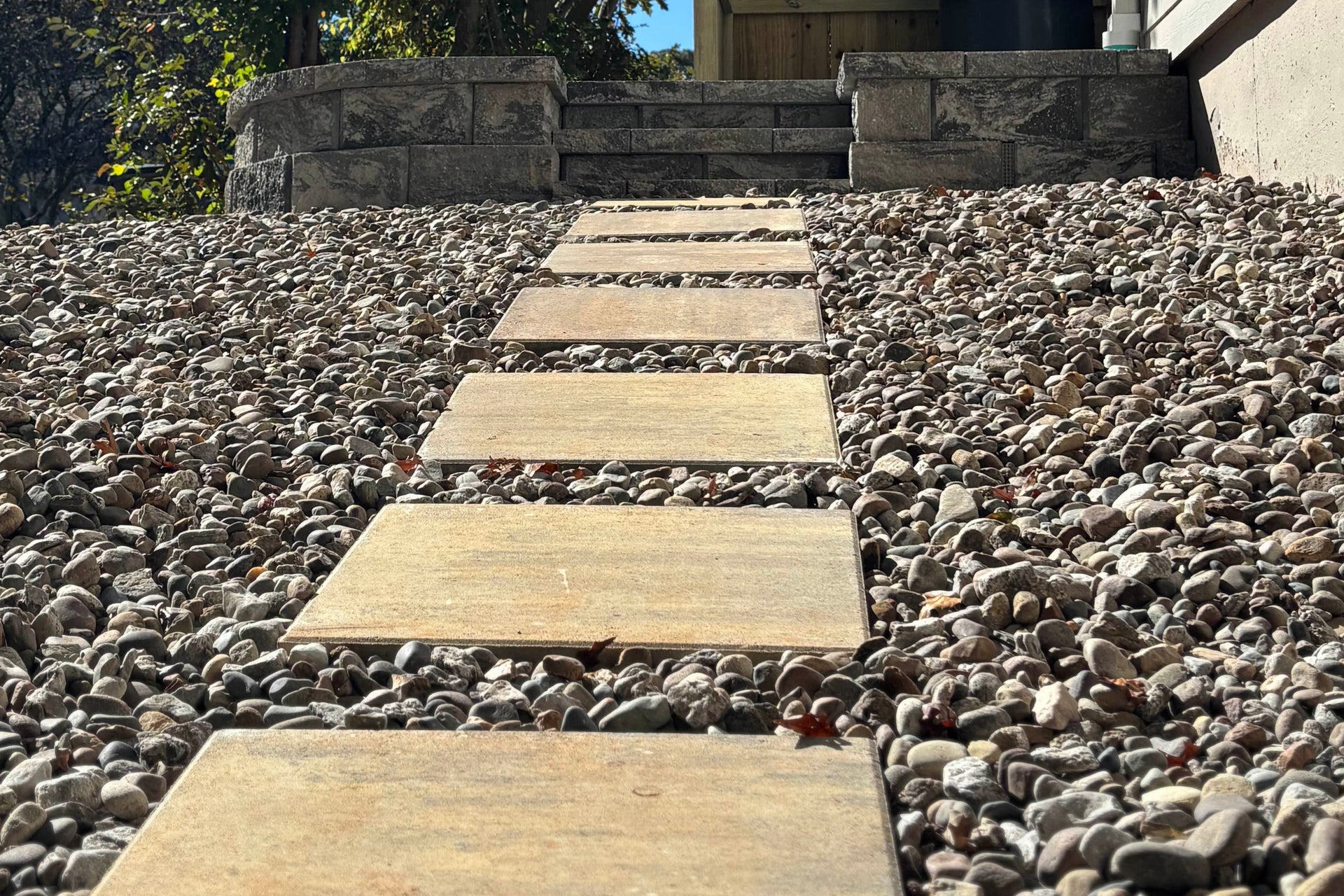 Stone steps leading up to a stone structure with pebbles on either side.
