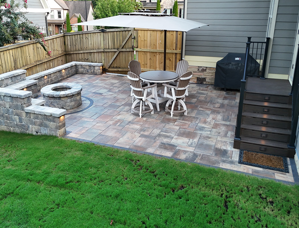 Backyard patio with fire pit, dining table, and chairs on a paved area with a new wooden fence.