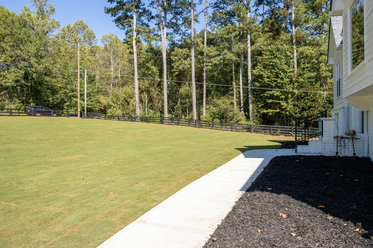 Lawn with a white house and trees in the background