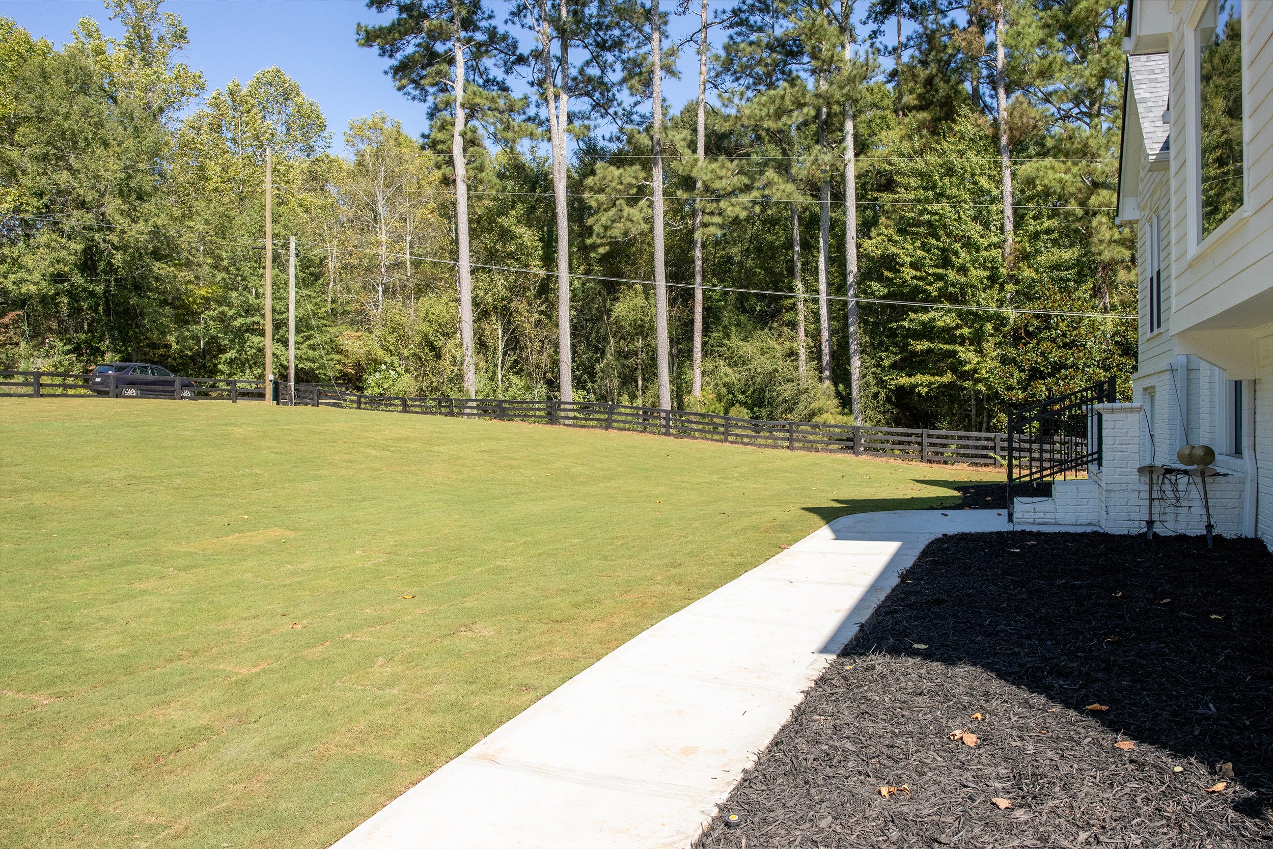 Lawn with a white house and trees in the background