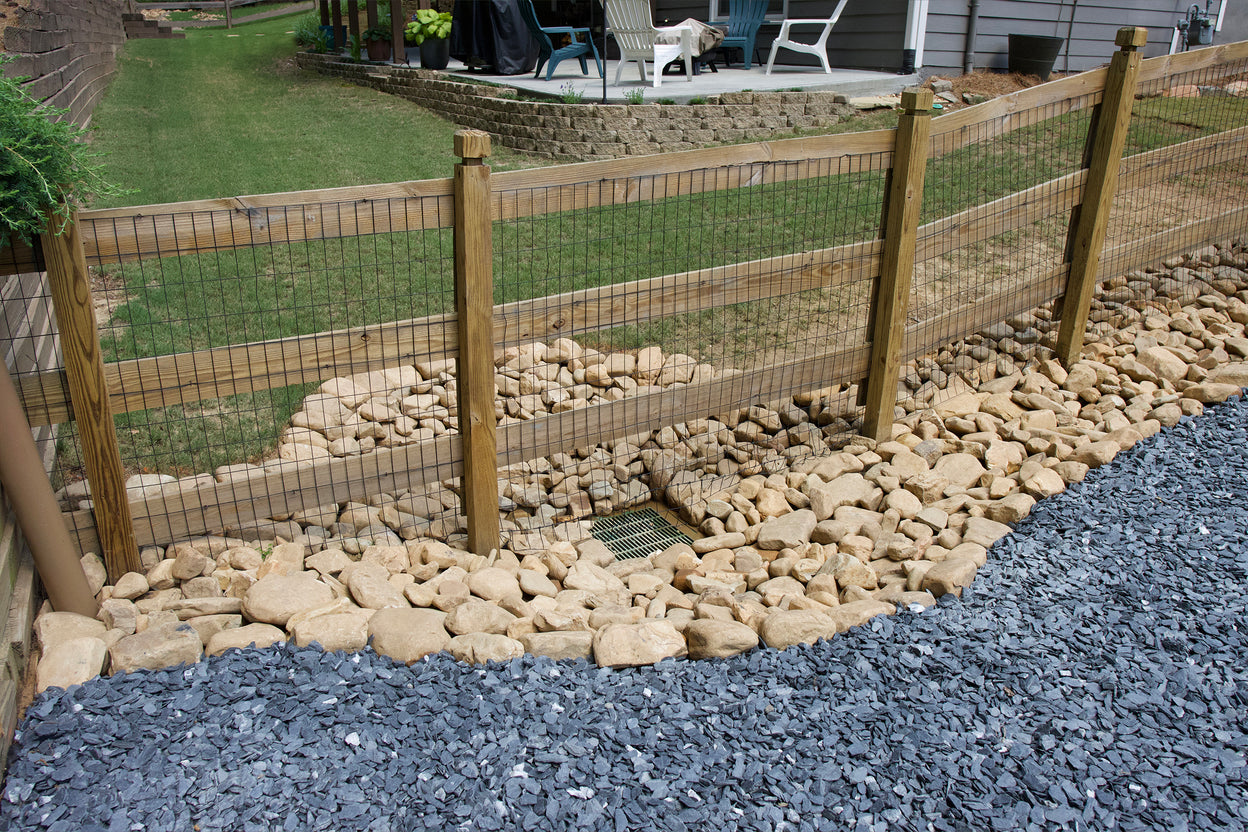 Custom wood and wire mesh fence with sturdy timber posts and cap rails, installed along a curved gravel and stone drainage swale that directs water away from the lawn and patio, professional fencing and drainage integration in Marietta, GA by Precision Grading & Hardscapes